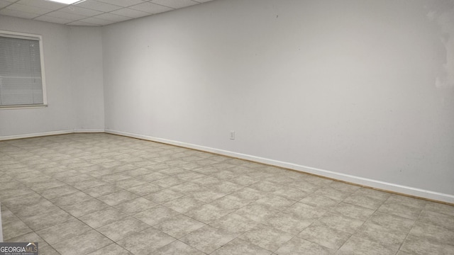 empty room featuring a drop ceiling, baseboards, and tile patterned floors