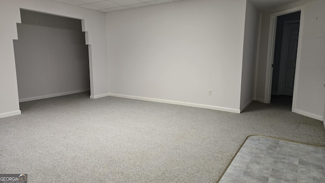 carpeted spare room with a drop ceiling and baseboards