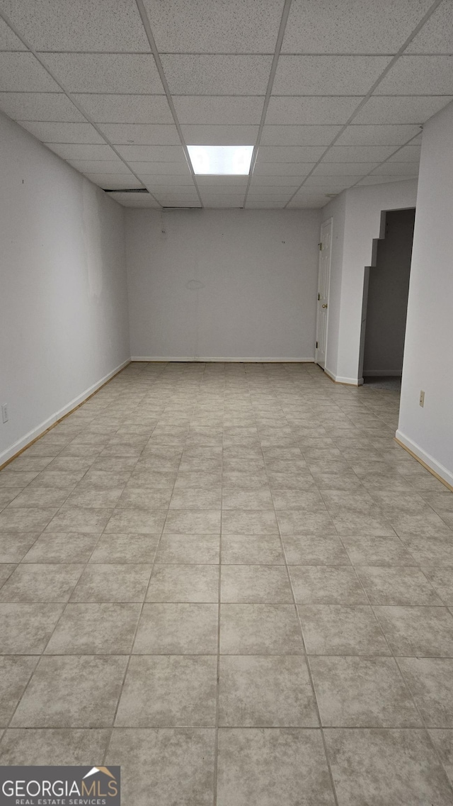 empty room featuring a drop ceiling and baseboards