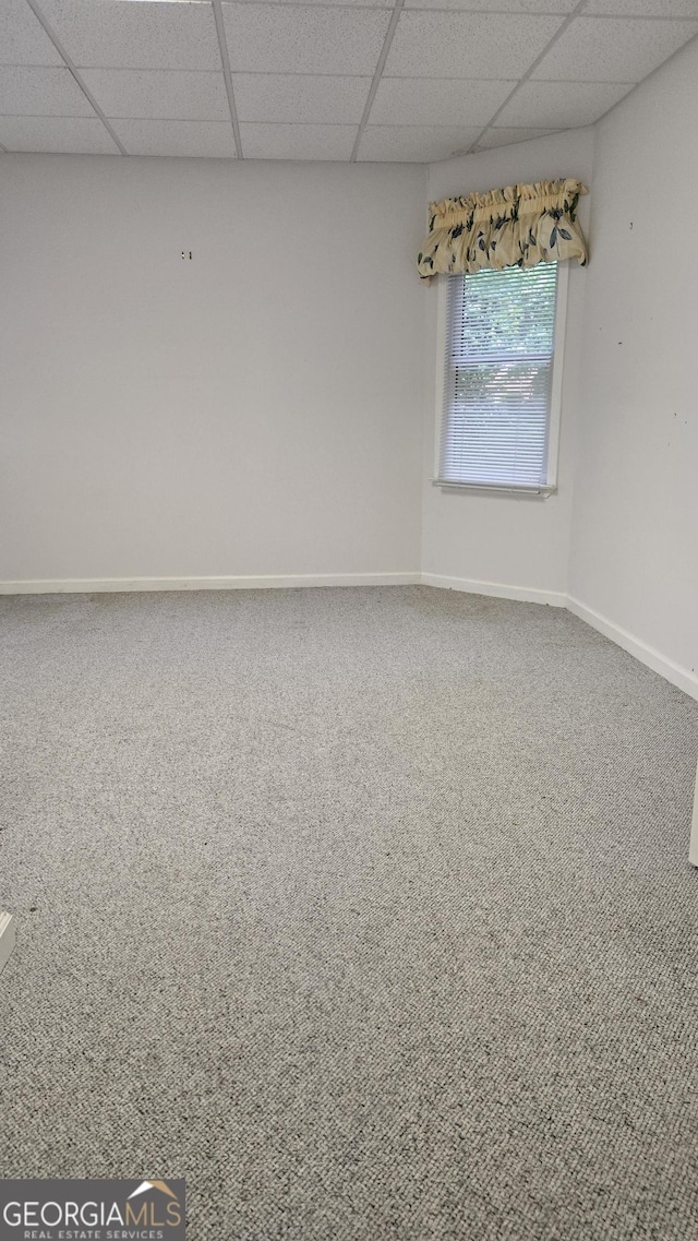 spare room featuring a paneled ceiling, carpet floors, and baseboards