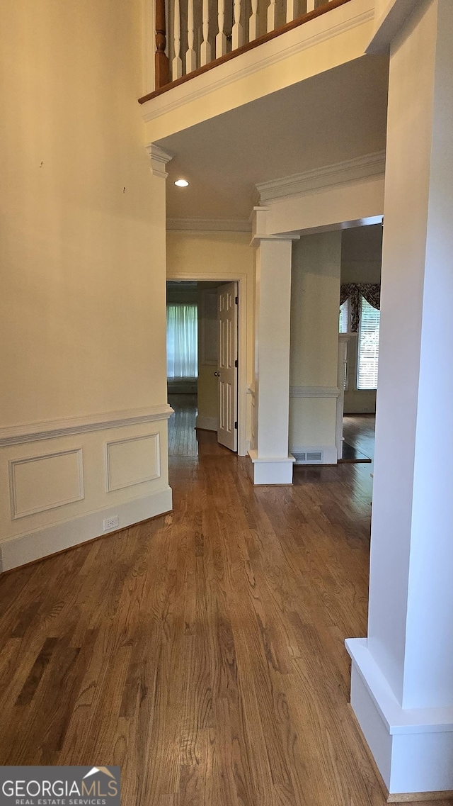 unfurnished dining area with ornamental molding, healthy amount of natural light, wood finished floors, and a towering ceiling