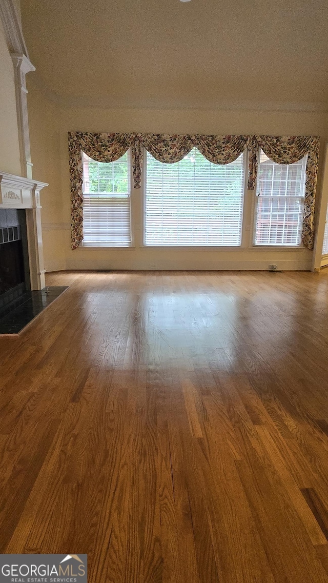 unfurnished living room featuring wood finished floors, a tiled fireplace, and a textured ceiling