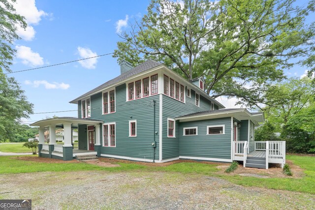409 N Jefferson Ave, Eatonton, GA 31024 - view of front facade with covered porch, a chimney, a wooden deck, and a shingled roof