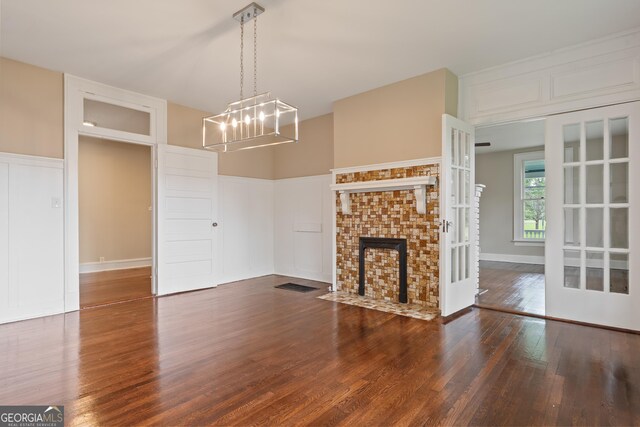409 N Jefferson Ave, Eatonton, GA 31024 - unfurnished living room with wood finished floors, a chandelier, a fireplace with flush hearth, and a decorative wall