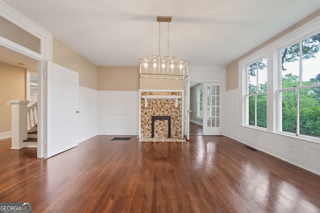 409 N Jefferson Ave, Eatonton, GA 31024 - unfurnished living room featuring a decorative wall, dark wood-type flooring, stairway, wainscoting, and a fireplace