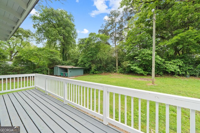 409 N Jefferson Ave, Eatonton, GA 31024 - wooden terrace featuring a storage unit, a lawn, an outbuilding, and view of wooded area
