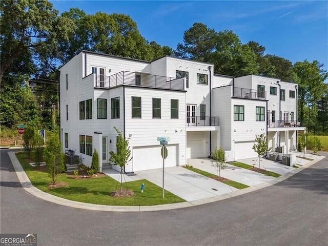 townhome / multi-family property with a balcony, an attached garage, driveway, and central AC