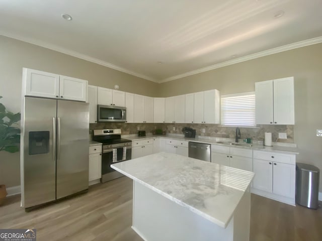 3812 Hartley Bridge Rd, Macon, GA 31216 - kitchen with appliances with stainless steel finishes, a sink, light wood-style flooring, white cabinetry, and ornamental molding