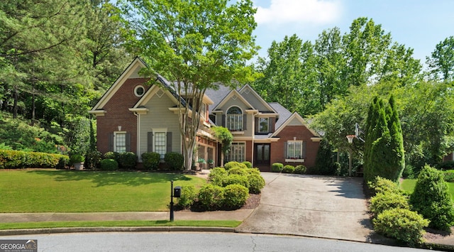 view of front facade with concrete driveway, a front yard, and brick siding