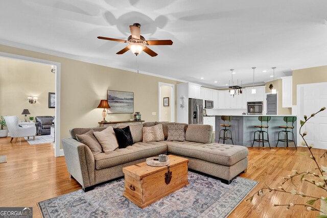 living area featuring a ceiling fan, crown molding, light wood-style flooring, and recessed lighting