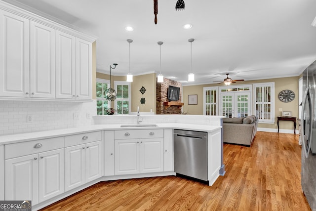 kitchen with a sink, dishwasher, a large fireplace, ceiling fan, and a peninsula