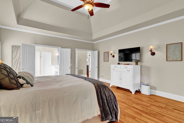 bedroom featuring a raised ceiling, light wood-style flooring, ornamental molding, and baseboards