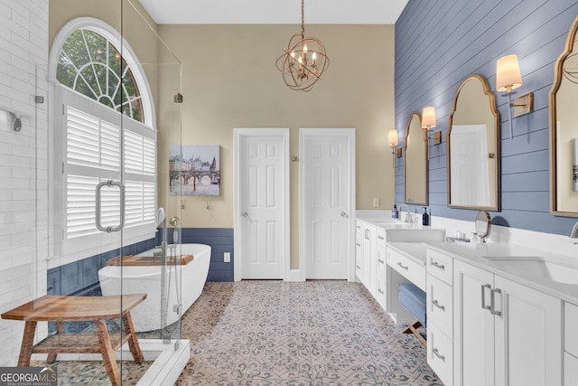 full bathroom featuring a high ceiling, a chandelier, a shower stall, a freestanding tub, and double vanity