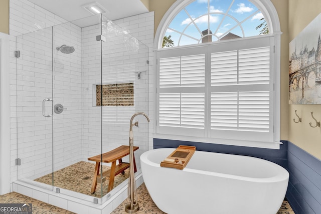 bathroom with healthy amount of natural light, a freestanding bath, and a stall shower