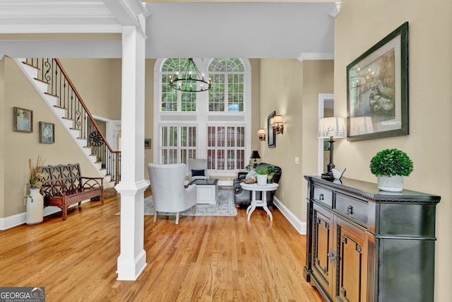 foyer entrance featuring crown molding, light wood-style floors, baseboards, stairway, and a chandelier