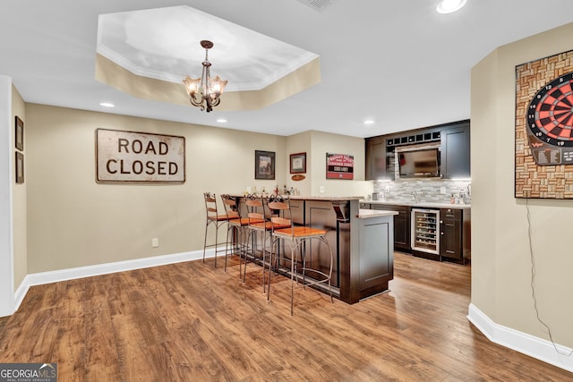 1477 Edenham Ln, Cumming, GA 30041 - indoor wet bar with wine cooler, wood finished floors, decorative backsplash, recessed lighting, and a tray ceiling