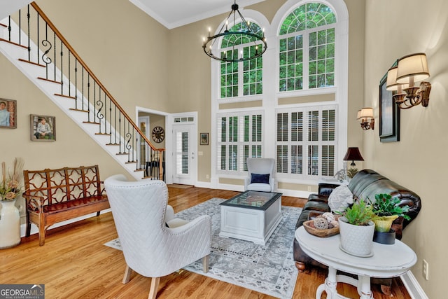 living area featuring a chandelier, stairway, a high ceiling, wood finished floors, and baseboards