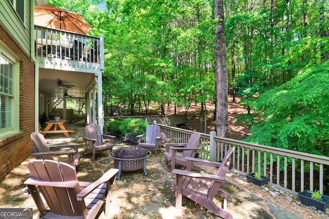 view of patio with an outdoor fire pit, a ceiling fan, and a balcony