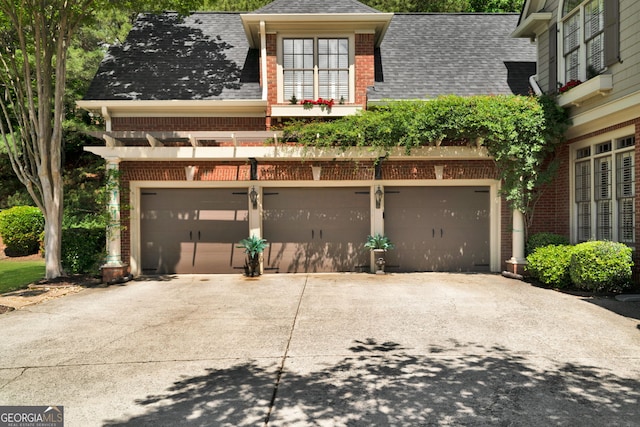 view of front of house featuring brick siding, roof with shingles, an attached garage, and concrete driveway