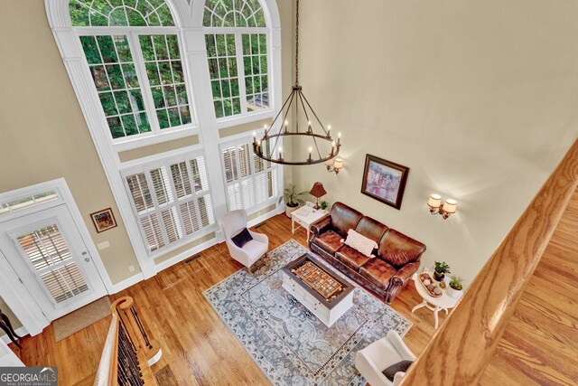 living room with a high ceiling, a chandelier, wood finished floors, and baseboards