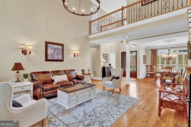living room with a chandelier, light wood finished floors, ornamental molding, and baseboards