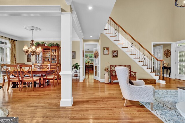 entryway with light wood-style floors, a chandelier, stairway, ornamental molding, and baseboards