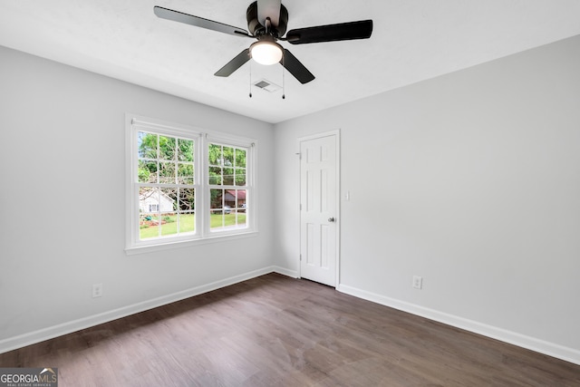 unfurnished room with dark wood-type flooring, a ceiling fan, and baseboards
