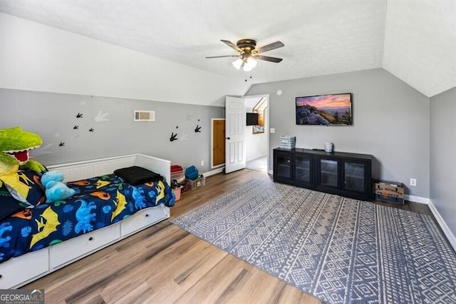 bedroom featuring wood finished floors, lofted ceiling, baseboards, and a ceiling fan