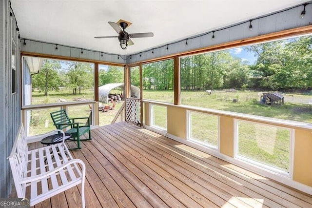 unfurnished sunroom featuring ceiling fan and view of scattered trees