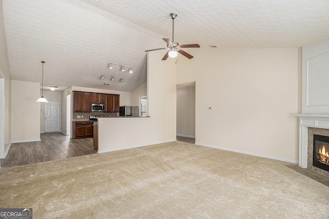 unfurnished living room featuring carpet, a fireplace, ceiling fan, baseboards, and high vaulted ceiling
