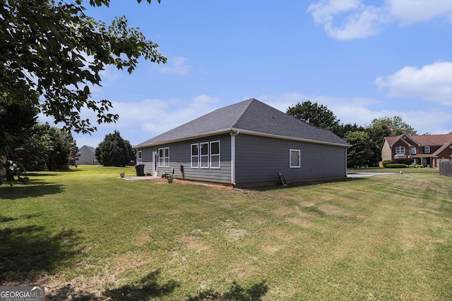 rear view of house with a yard and roof with shingles