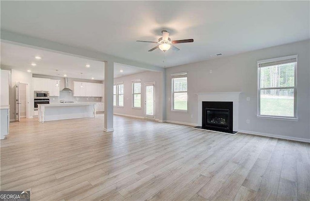 160 Cooper Cv W Lot 64, Fayetteville, GA 30215 - unfurnished living room with ceiling fan, light wood finished floors, a glass covered fireplace, plenty of natural light, and recessed lighting