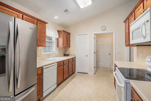 807 Ideal Pl, Winder, GA 30680 - kitchen featuring white appliances, vaulted ceiling, backsplash, light flooring, and a sink