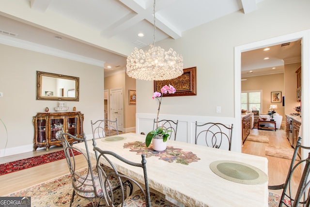 dining room with light wood finished floors, beam ceiling, recessed lighting, ornamental molding, and a chandelier