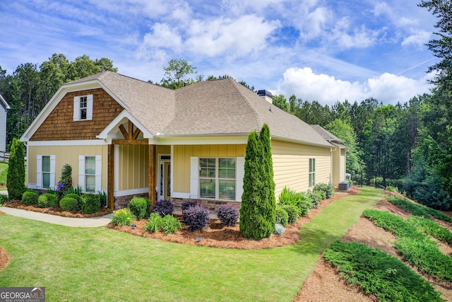 craftsman house featuring a front lawn, a chimney, roof with shingles, and board and batten siding