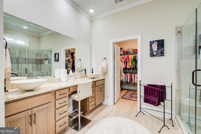 full bath with crown molding, a stall shower, wood finished floors, double vanity, and a spacious closet