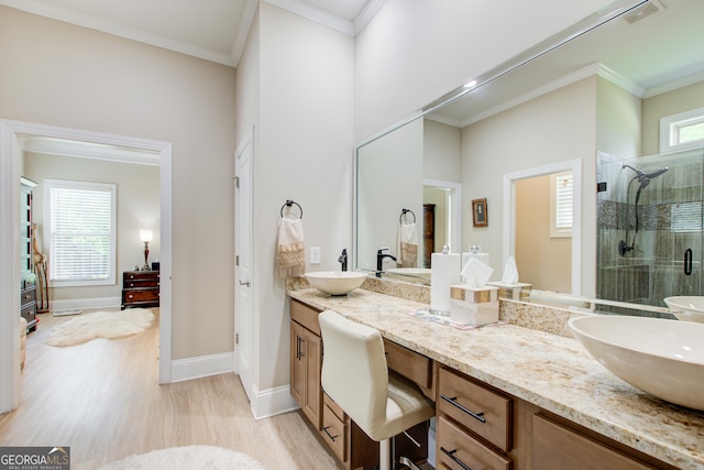 full bath with a stall shower, wood finished floors, double vanity, baseboards, and crown molding