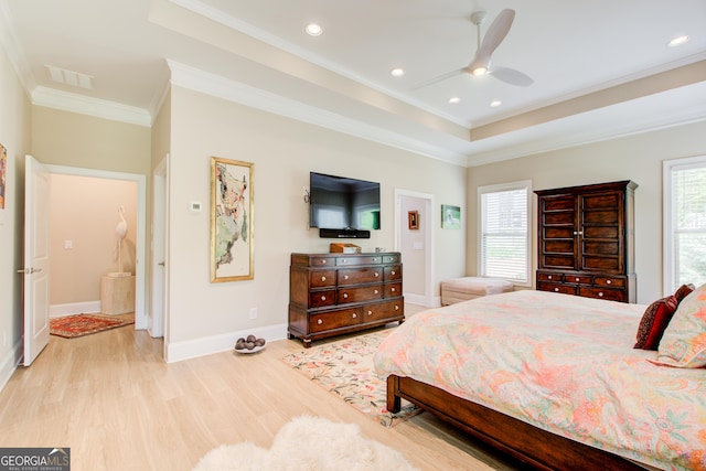 bedroom featuring crown molding, light wood-type flooring, baseboards, a tray ceiling, and ceiling fan