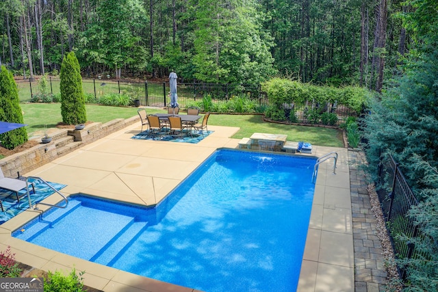 view of swimming pool with a patio area and a wooded view