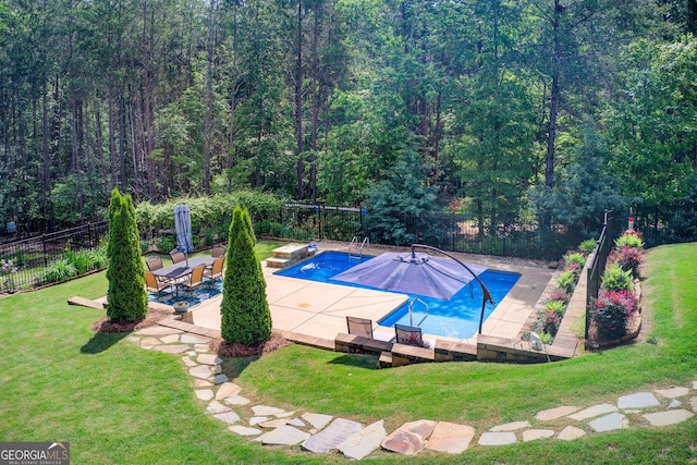 view of pool with a patio area and a wooded view