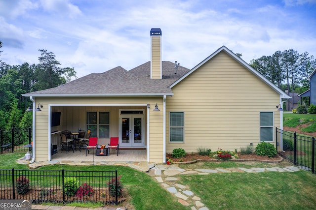 back of property with a chimney, a patio, french doors, and a shingled roof