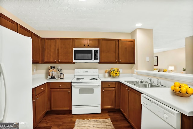 132 Tara Commons Dr, Loganville, GA 30052 - kitchen with white appliances, a sink, dark wood-style flooring, light countertops, and a peninsula