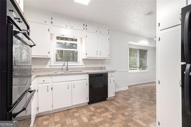 kitchen with black appliances, a sink, white cabinets, baseboards, and brick patterned flooring