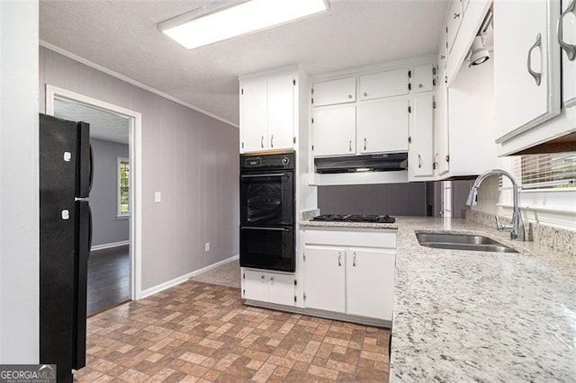 kitchen with a sink, black appliances, ornamental molding, white cabinets, and brick patterned floors