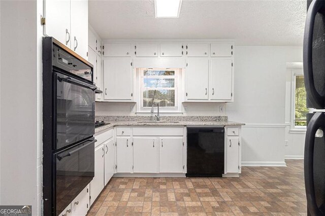kitchen featuring black appliances, a sink, brick patterned flooring, white cabinetry, and a textured ceiling