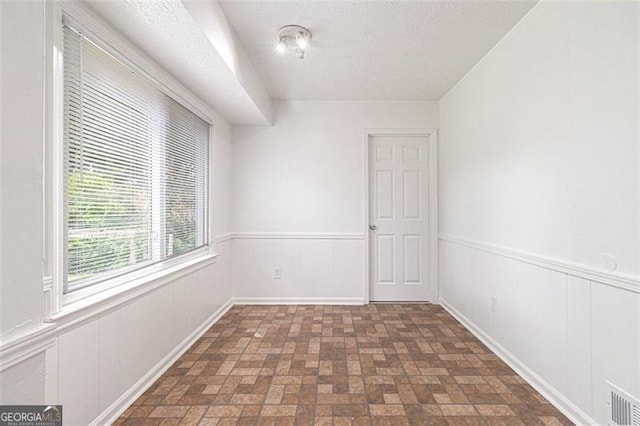 unfurnished room with brick patterned floors and wainscoting
