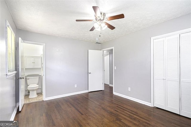 unfurnished bedroom featuring wood finished floors, baseboards, a textured ceiling, a closet, and connected bathroom