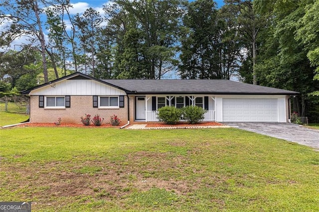 ranch-style home with an attached garage, asphalt driveway, brick siding, a front yard, and board and batten siding