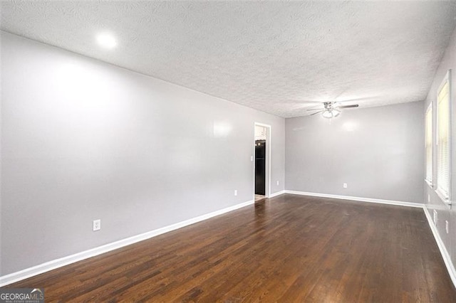 spare room featuring a ceiling fan, dark wood-type flooring, a textured ceiling, and baseboards