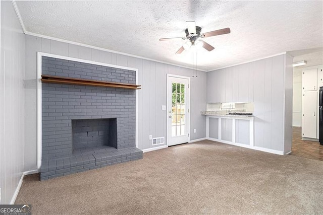 unfurnished living room with ceiling fan, carpet, crown molding, a textured ceiling, and a fireplace